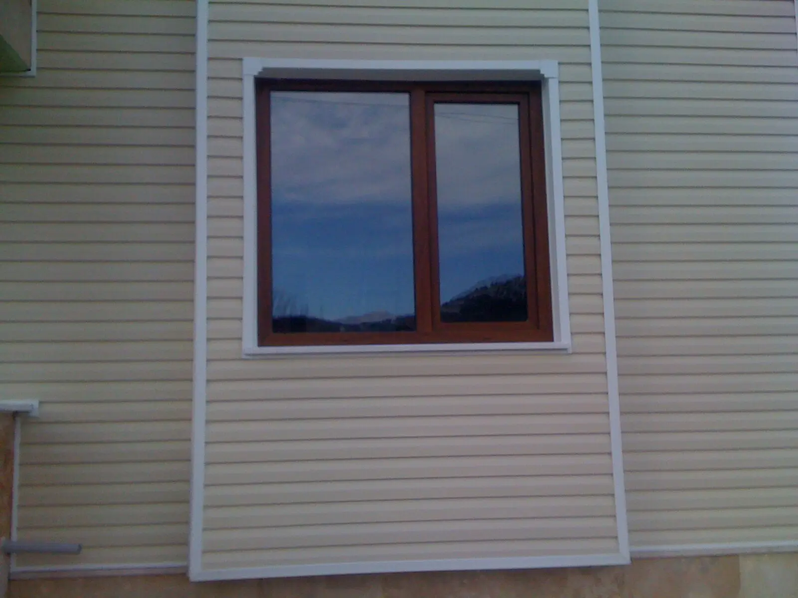 Siding kaplamalı cephede ahşap desenli PVC pencere
